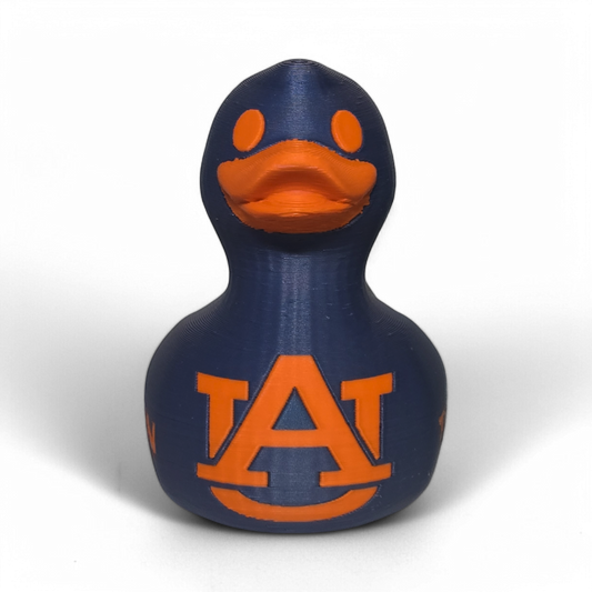 A small 3D printed PLA duck figurine in navy blue with orange accents, featuring the letters 'UA' and the word 'TIGERS' on the front, photographed on a light gray background.
