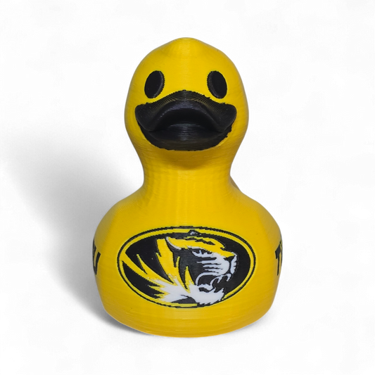 A bright yellow 3D Printer PLA duck with a black beak and black printed graphics, including a tiger logo and the word 'TIGERS' on the side, shown on a plain white background.
