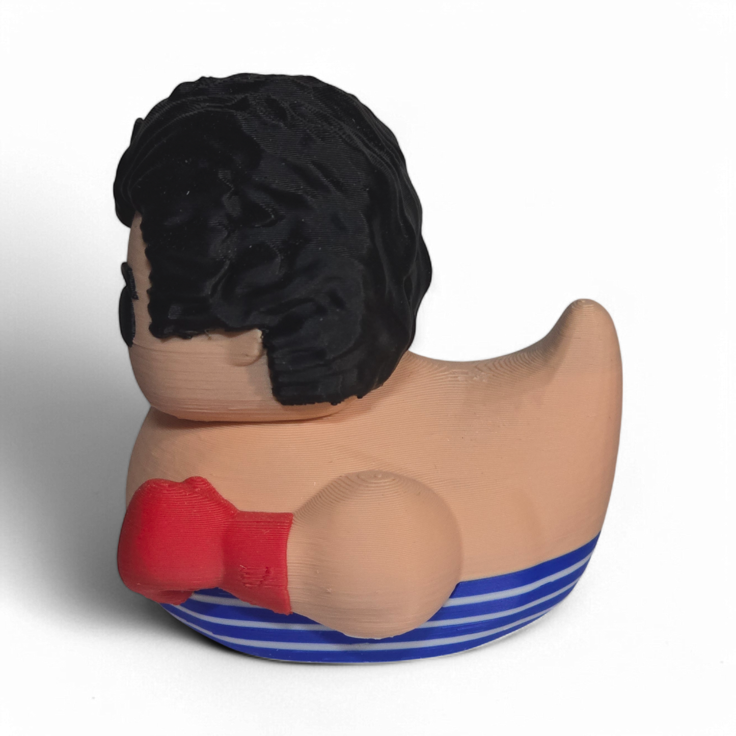 A novelty 3D Printed PLA duck shaped like a cartoon boy with black hair, a beige body, red boxing gloves, and blue-and-white striped shorts, photographed on a plain white background.