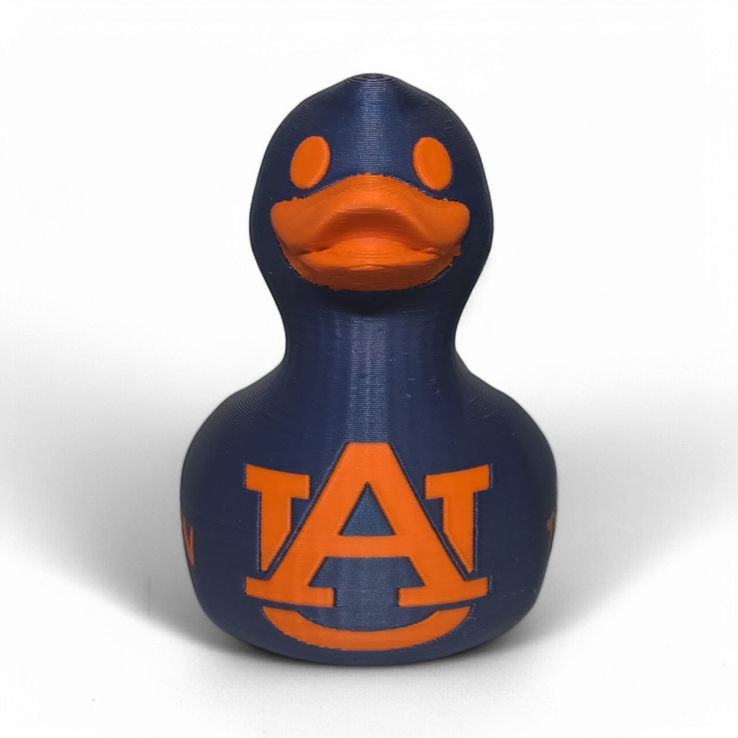 A small 3D printed PLA duck figurine in navy blue with orange accents, featuring the letters 'UA' and the word 'TIGERS' on the front, photographed on a light gray background.