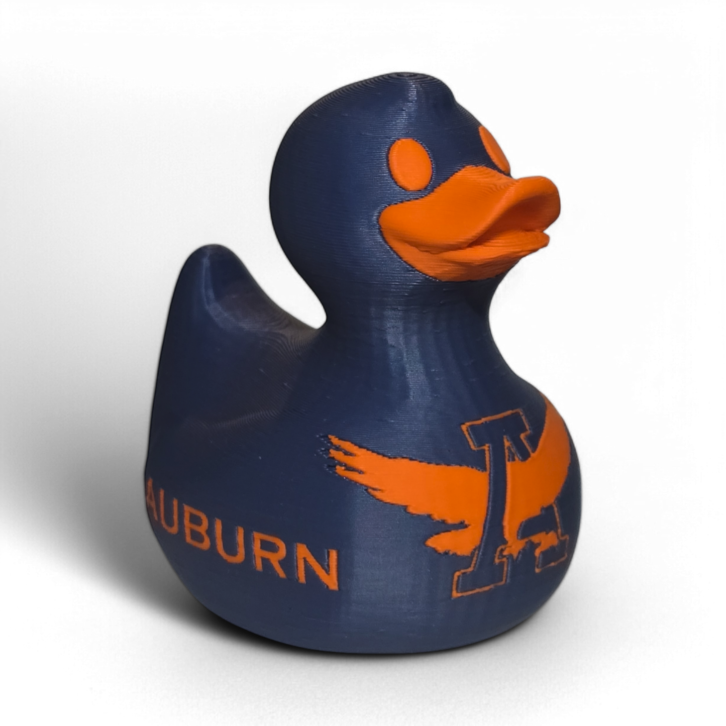 A small 3D printed PLA duck figurine in navy blue with orange accents, featuring the letters 'UA' and the word 'TIGERS' on the front, photographed on a light gray background.
