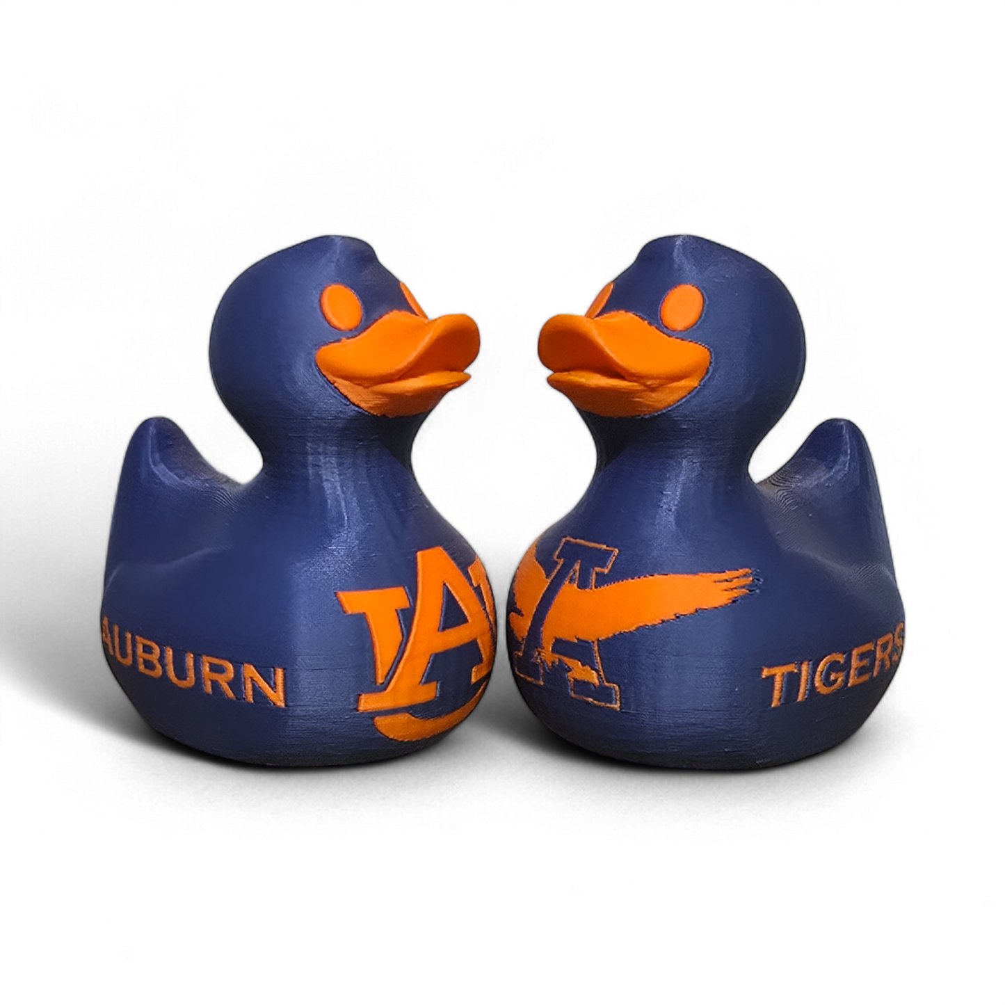 Two blue 3D printed PLA ducks with orange beaks and orange Auburn Tigers graphics, shown on a clean white background.