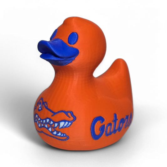 An orange 3D printed PLA duck with blue painted details, including a blue beak, blue eye, and blue Florida Gators logo and script on the side, shown on a white background.