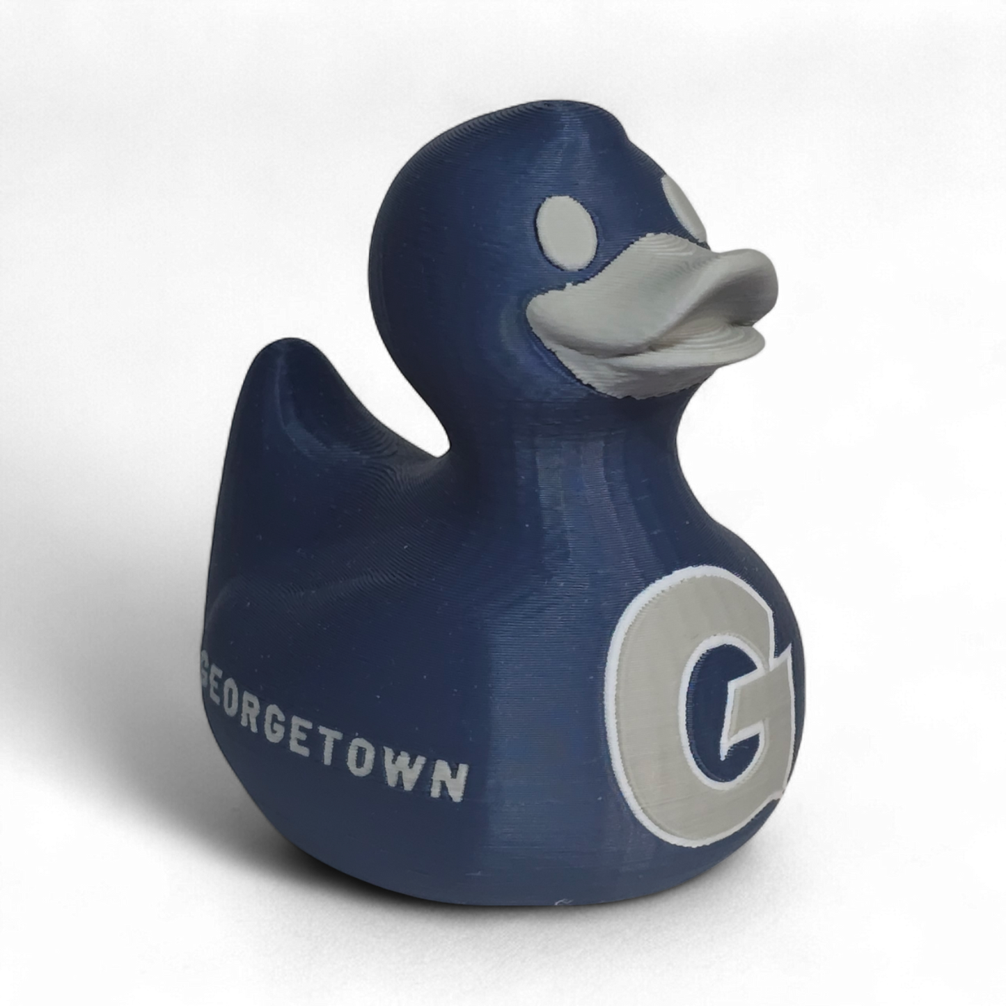 A dark blue 3D printed PLA duck toy featuring the white letters 'G' and 'HOYAS' on its side, with a gray beak and eye, set against a plain white background.