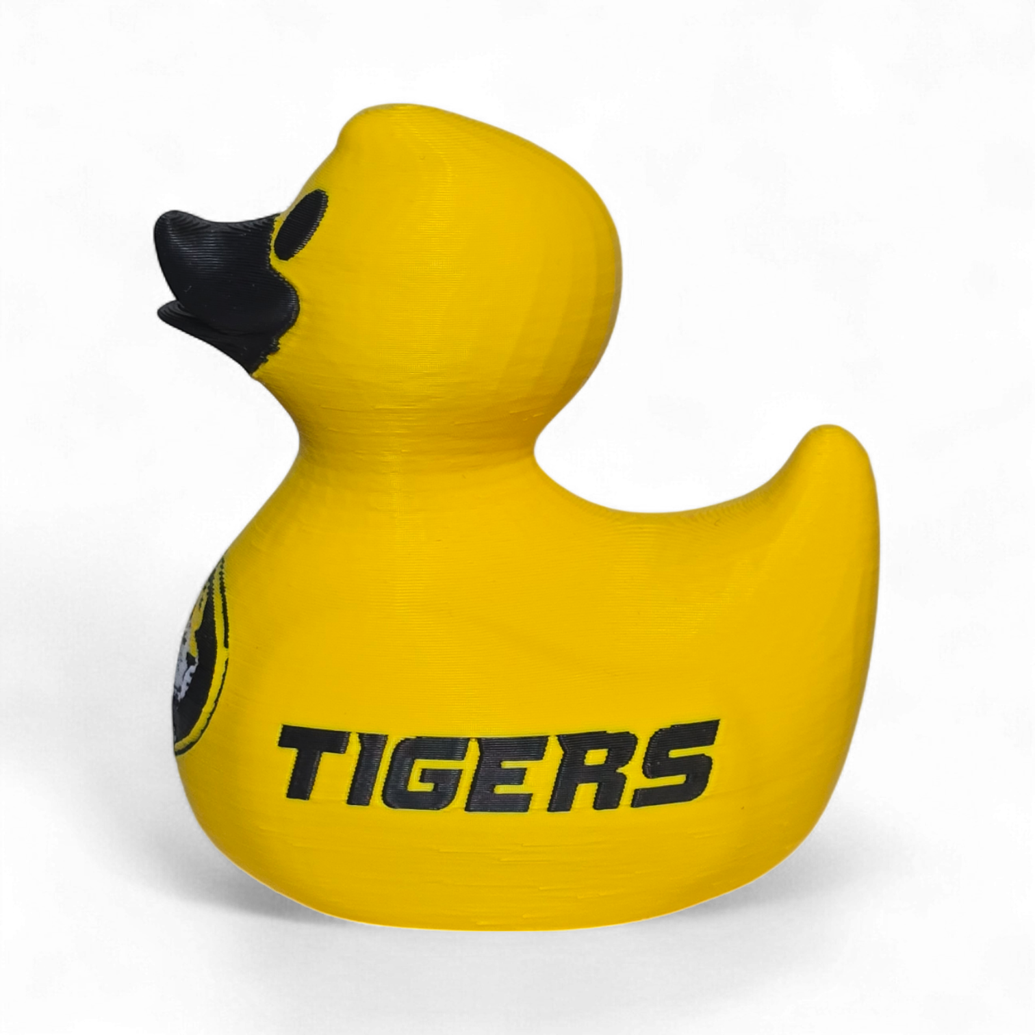 A bright yellow 3D Printer PLA duck with a black beak and black printed graphics, including a tiger logo and the word 'TIGERS' on the side, shown on a plain white background.