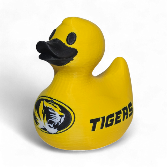 A bright yellow 3D Printer PLA duck with a black beak and black printed graphics, including a tiger logo and the word 'TIGERS' on the side, shown on a plain white background.