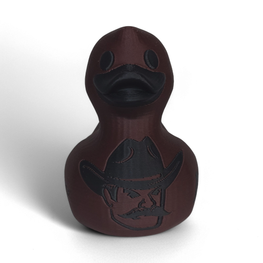 A dark brown 3D Printed PLA duck with a matte finish, featuring a black embossed cowboy hat logo and the word 'AGGIES' on the side, set against a plain white background.