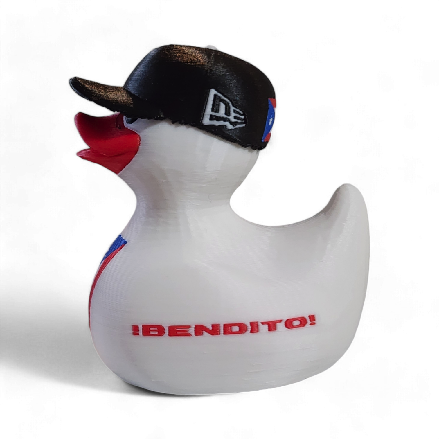 A white 3D printed duck wearing a black baseball cap with a white New Era logo, featuring a red beak and a Puerto Rico flag graphic on its side, with the red text '¡BENDITO' printed on the front.