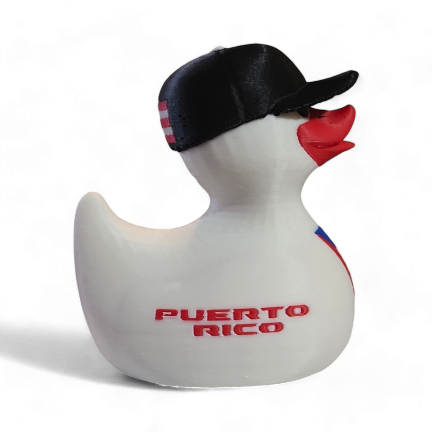 A white 3D printed duck wearing a black baseball cap with a white New Era logo, featuring a red beak and a Puerto Rico flag graphic on its side, with the red text '¡BENDITO' printed on the front.