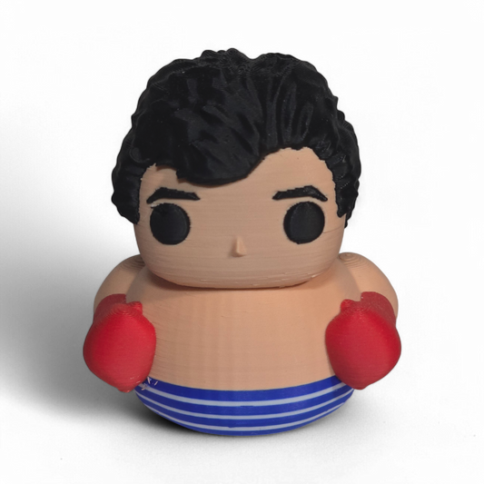 A novelty 3D Printed PLA duck shaped like a cartoon boy with black hair, a beige body, red boxing gloves, and blue-and-white striped shorts, photographed on a plain white background.