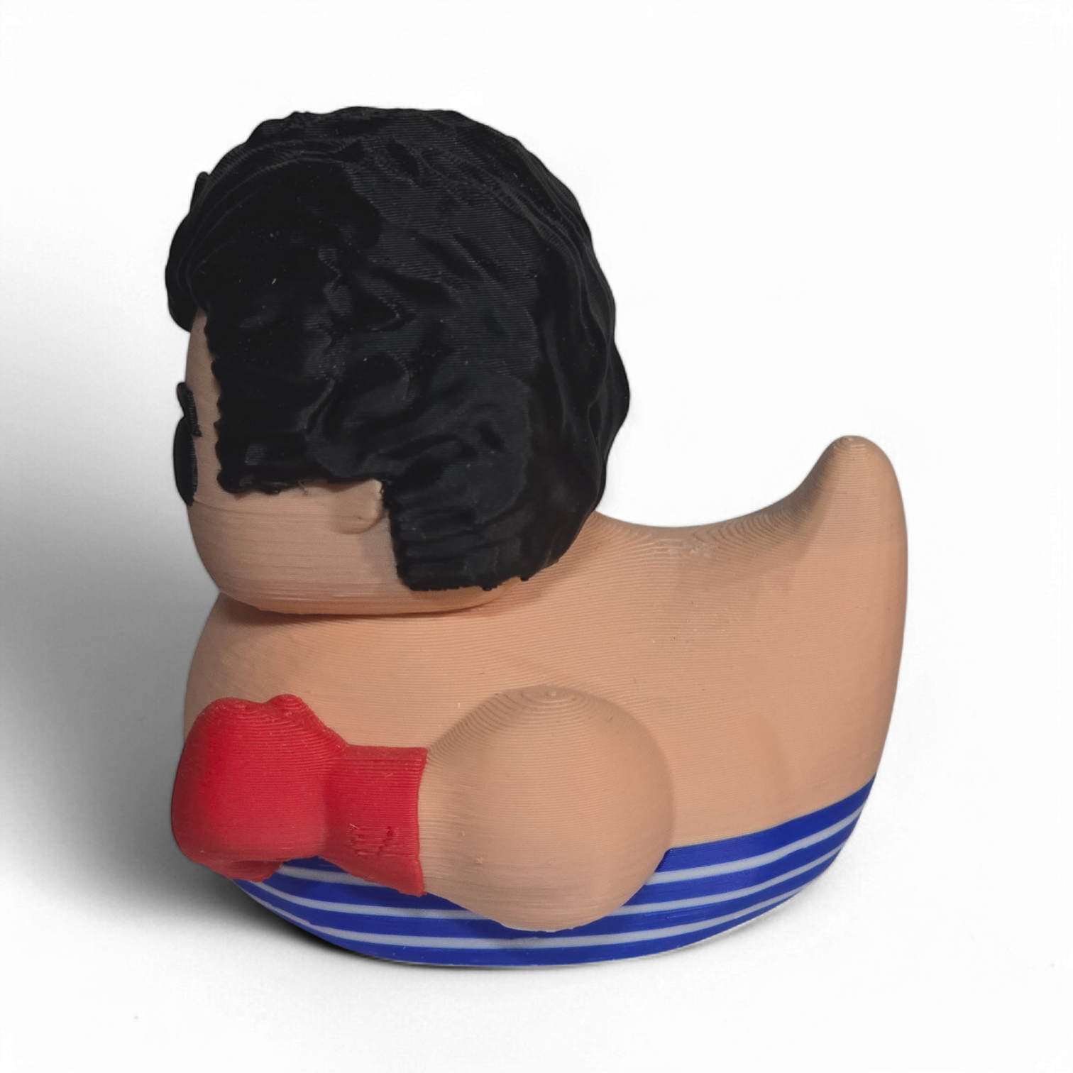 A novelty 3D Printed PLA duck shaped like a cartoon boy with black hair, a beige body, red boxing gloves, and blue-and-white striped shorts, photographed on a plain white background.