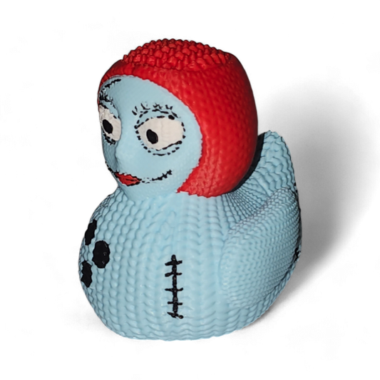 A 3D Printed PLA duck, featuring a light blue body with black spots and a stitched seam, topped with a bright red textured head resembling hair, and detailed with cartoon eyes and a smile.