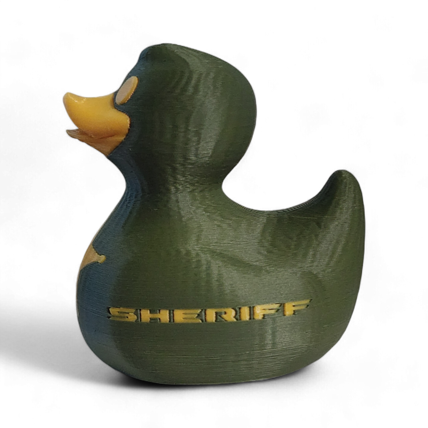 A 3D-printed 3D printed PLA duck styled as a sheriff's deputy, featuring an olive green body, a yellow beak and eye, a yellow sheriff's star badge on its side, and the word 'SHERIFF' printed in yellow.