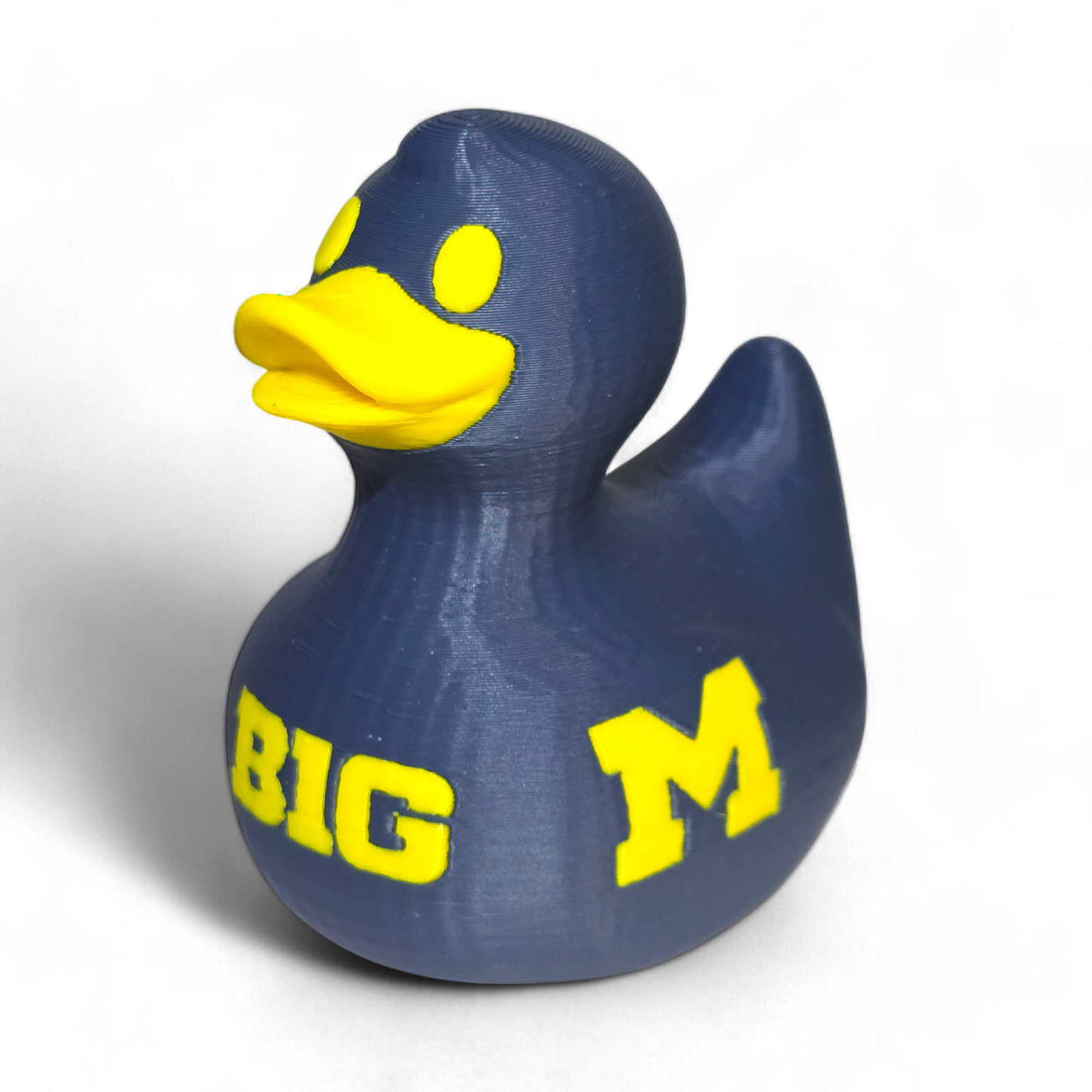 A 3D-printed PLA duck in navy blue with bright yellow accents, featuring the letters 'BIG' and 'M' representing the University of Michigan, on a plain white background.