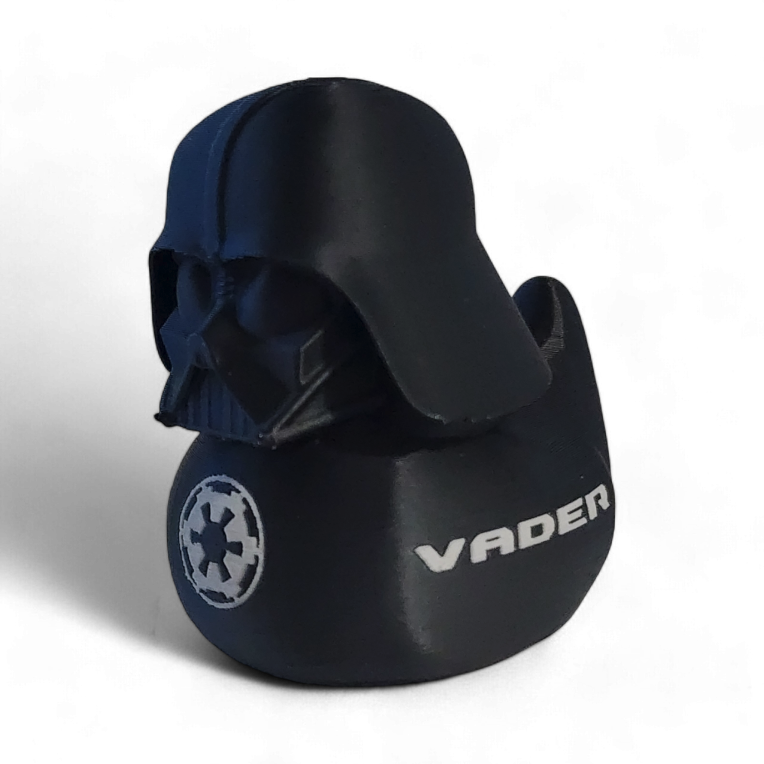 A Darth Vader themed helmet-shaped 3D printed PLA duck , featuring the white Star Wars VADER logo and an Imperial crest on the side, set against a plain white background.