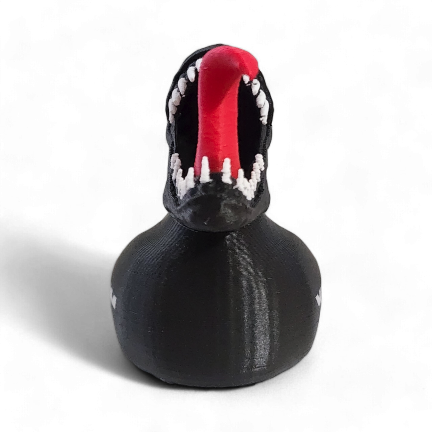 A black 3D Printed PLA duck with a Venom-themed design, featuring a red tongue sticking out, white teeth, a white and black pattern on the head, and the word 'VENOM' printed in white on the side.