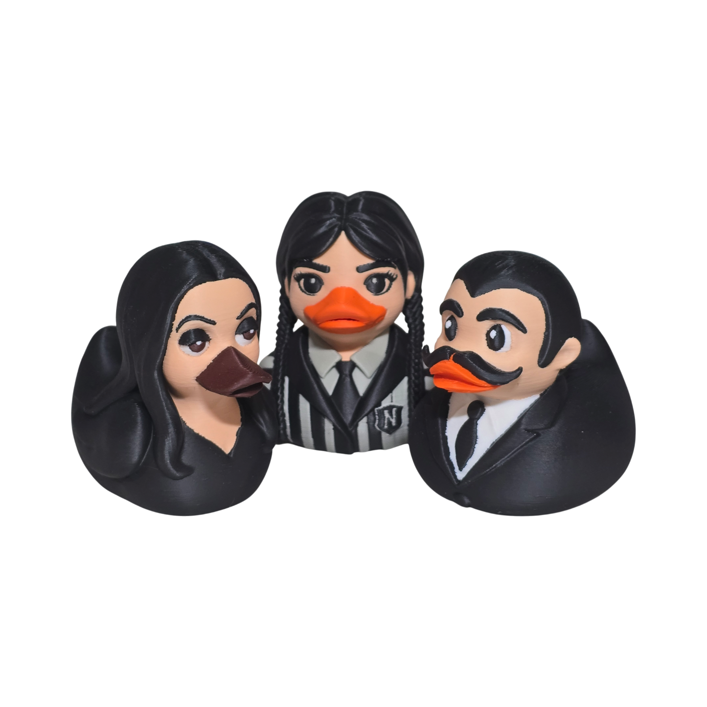 Three duck-shaped rubber ducks styled as characters with black hair and black clothing, featuring orange beaks and distinct facial features, set against a plain white background.
